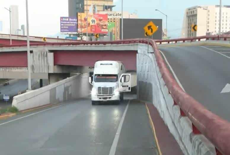 Queda tráiler atorado bajo puente Queda tráiler atorado bajo puente